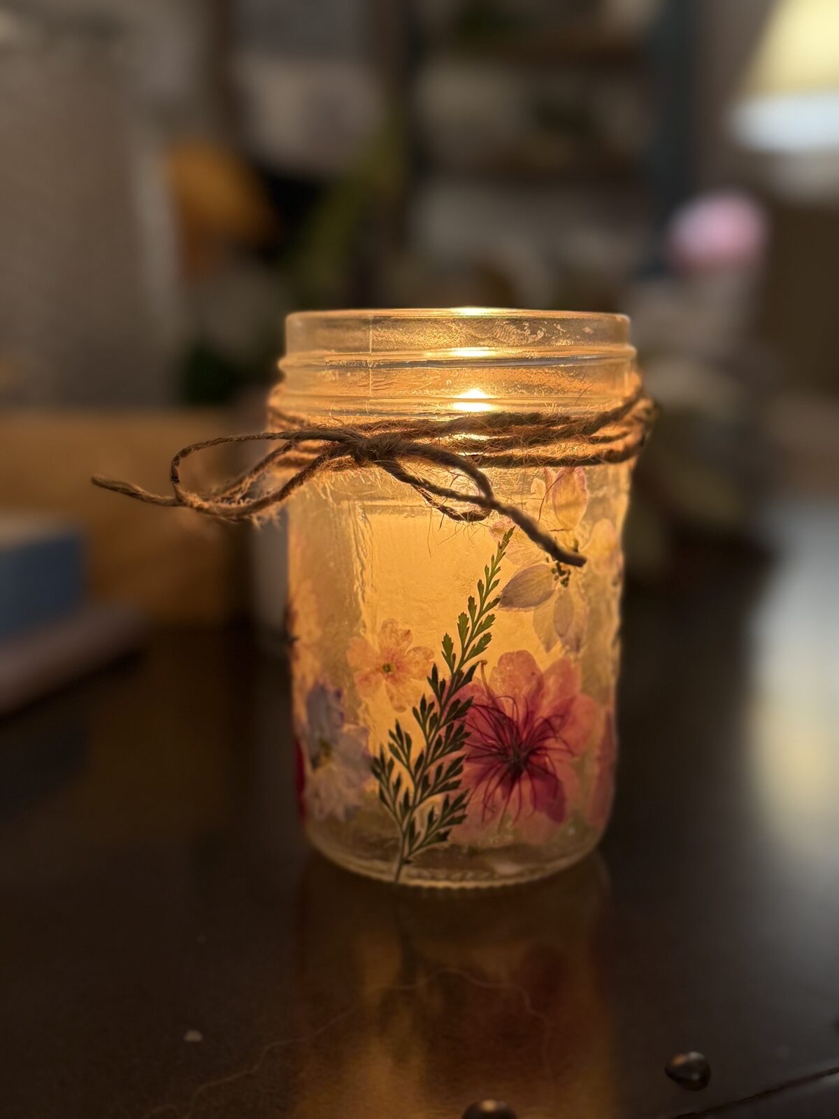 Glowing mason jar lantern with pressed flowers and twine bow